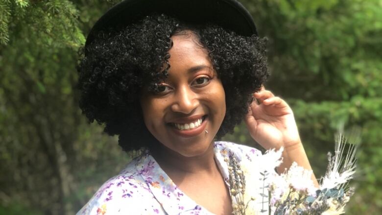 Black female author with dark hair and a black hat on.