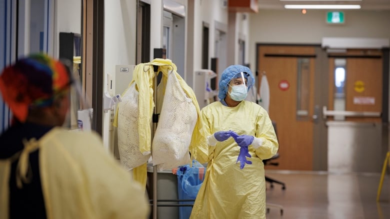 A nurse in a personal protective equipment walks down a hospital corridor.