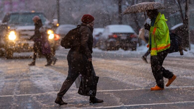 Pedestrians cross a road in the snow