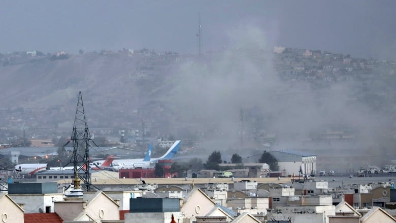 Smoke is seen billowing up from an airport against the backdrop of a mountain