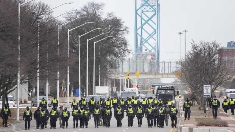 Police line up to remove protestors during Ambassador Bridge blockade