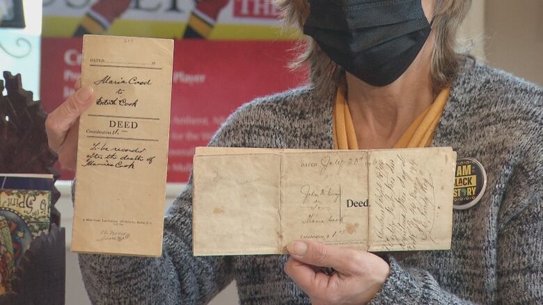 A person holds up two house deeds with signatures