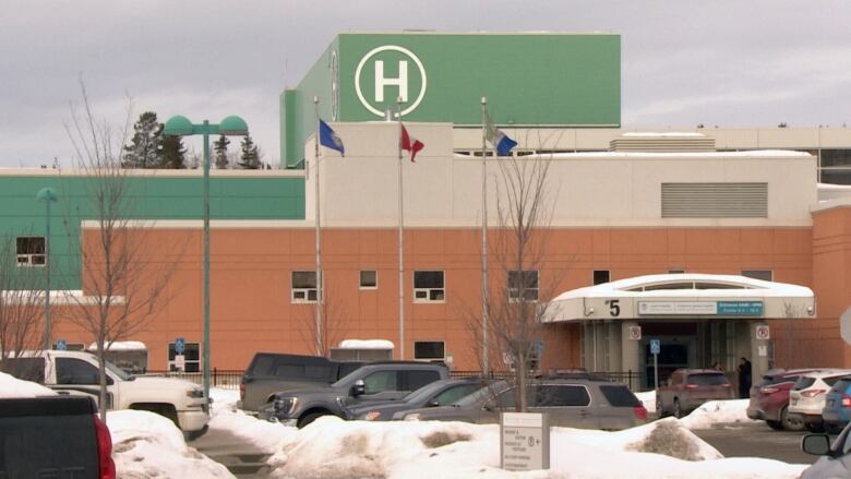 A cream and green coloured building with a big letter H on it.