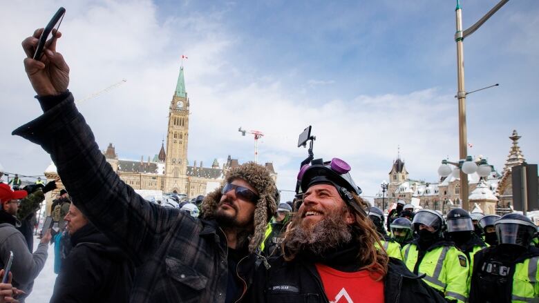 Two men take a selfie during a protest in front of Parliament Hill in Ottawa.