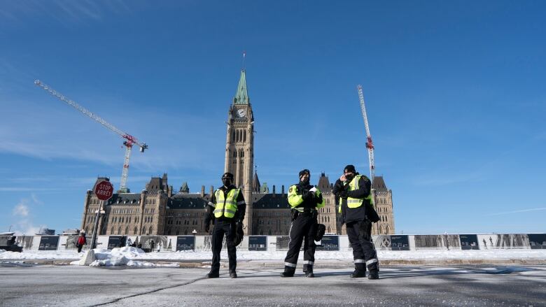 Three officers stand on Parliament Hill.