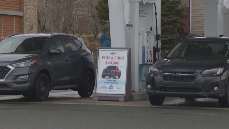 Two cars sit as a gas station.