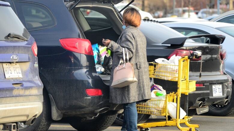 A woman loads groceries into the trunk of her car.