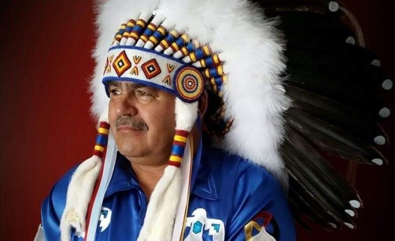 An Indigenous chief wears a head dress.