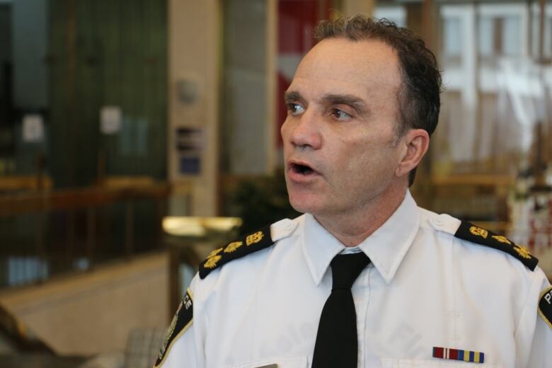 A man in a police uniform with dark hair looks off to the side.