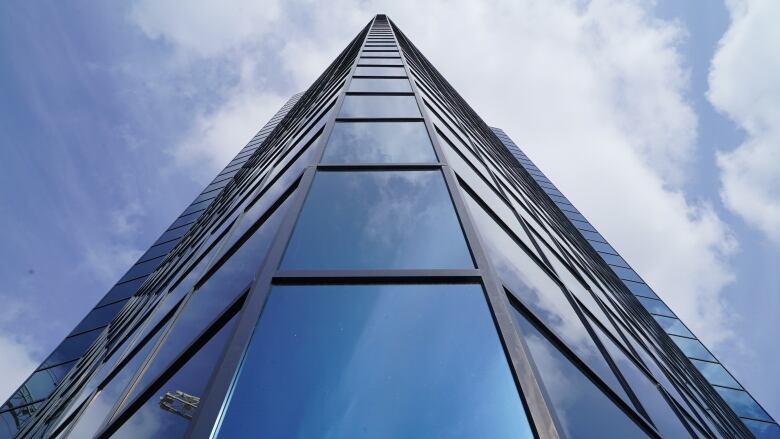 A glass office tower is shown against a blue sky.