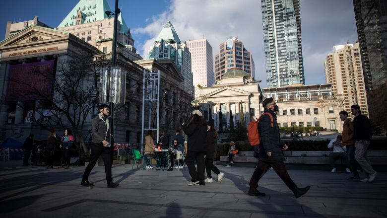 People walk through Robson Square near the Vancouver Art Gallery in Vancouver on a sunny day.