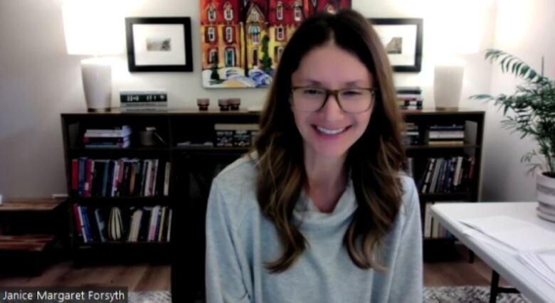 A woman smiles as she looks down during Zoom call.