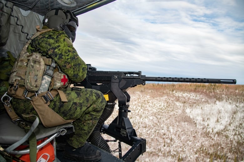 Corporal Nicolaus Lalopoulos, a Door Gunner with 408 Tactical Helicopter Squadron, mans a Browning M2 .50 Caliber Heavy Machine Gun on a CH-146 Griffon training flight during Joint Pacific Multinational Readiness Center 22-02 at Fort Wainwright, Alaska on March 8, 2022.