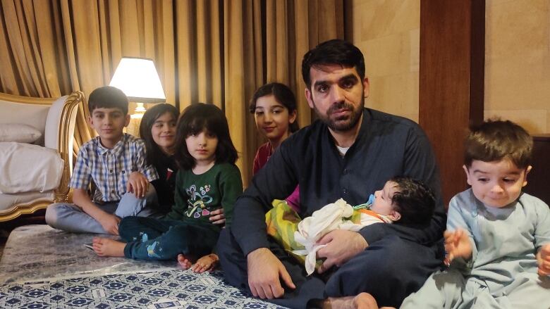 Mohammad Nasimi and his children pose in the hotel room in Islamabad where they're staying, until they can move to Canada. 