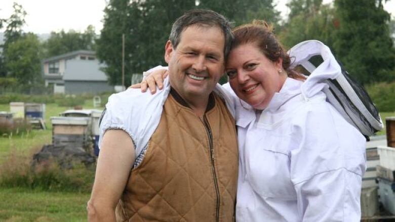 Husband and wife in beekeeper outfit pose for a photo