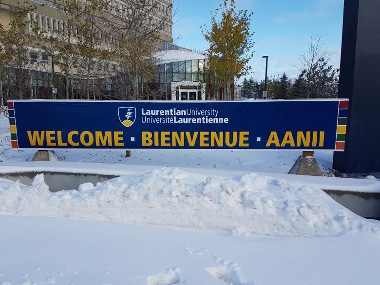 A blue banner with yellow lettering that says Laurentian University, Welcome, Bienvenue, Aanii with a snowbank in front of it.