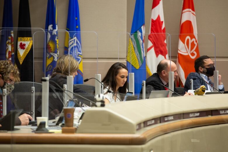 Men and women sit as the desks in the Calgary Council chambers.