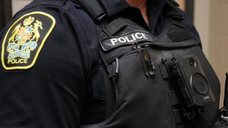 Closeup of male officers' upper chest, wearing a vest with a small black camera affixed to the vest.