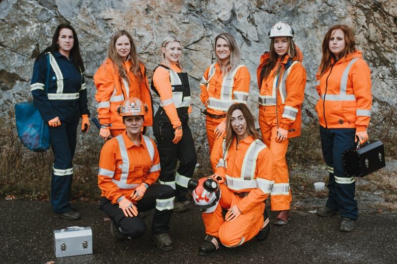 A group of women wearing orange coveralls.