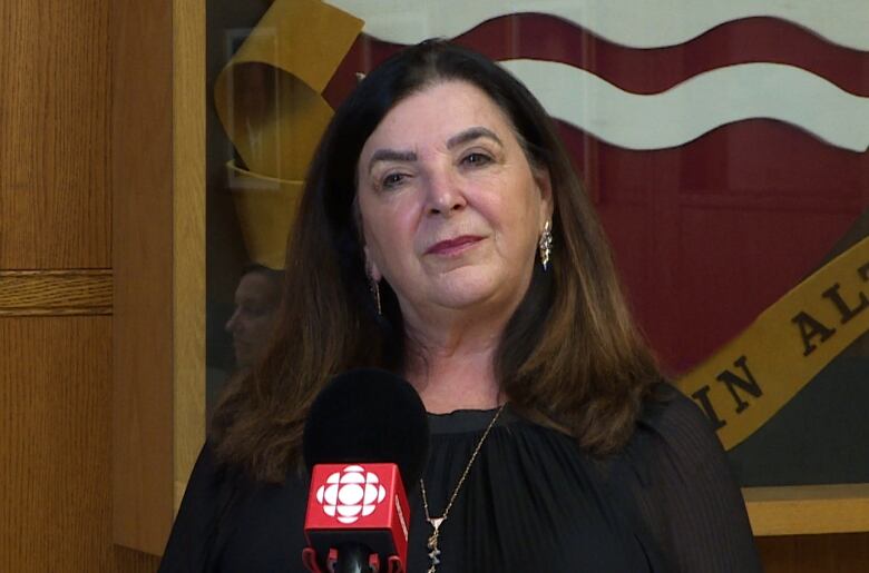 Vianne Timmons stands next to the Memorial University ceremonial coat of arms. 