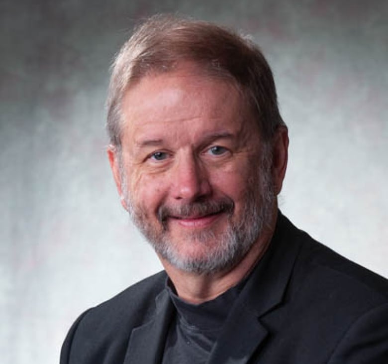 A portrait photo of a bearded man.