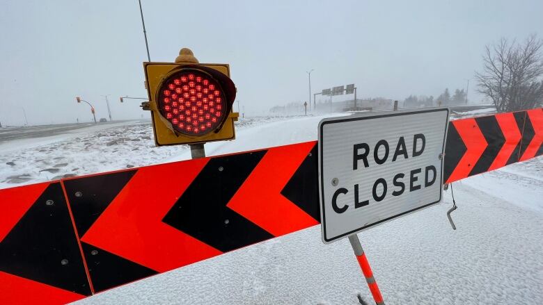 A barrier with a 'road closed' sign on the Trans-Canada Highway due to a blizzard.