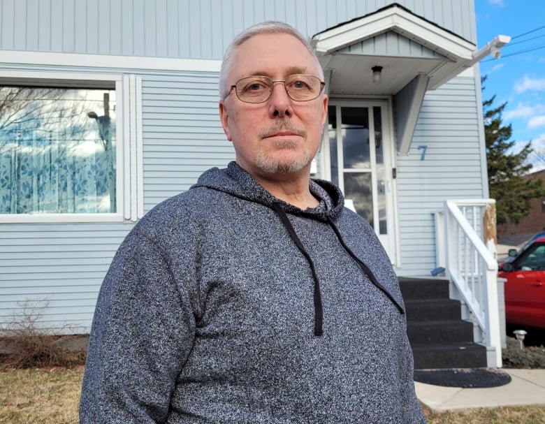 A man stands outside in front of his house.