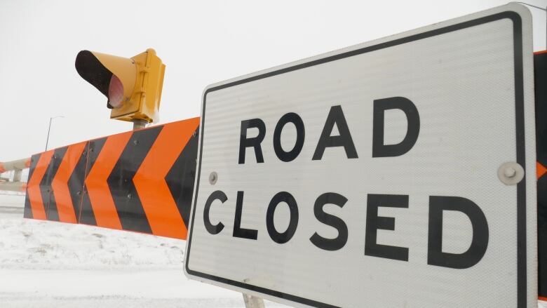 A closeup shows an orange and black striped traffic arm with a sign reading 