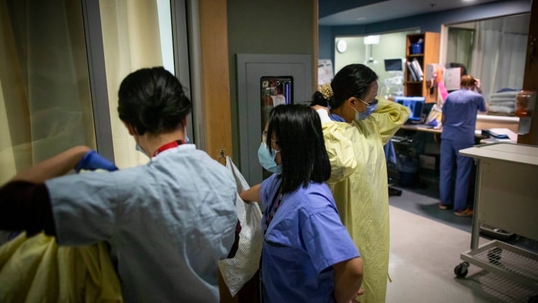 Nurses put on gowns in a hospital.