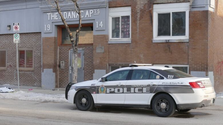 A police vehicle is parked in front of an apartment building in Winnipeg. 