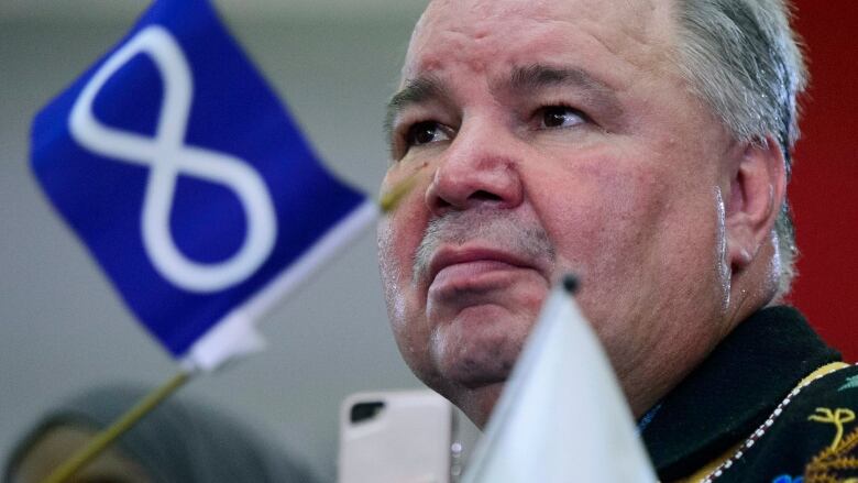 A politician with a miniature Mtis flag on his desk beside him.