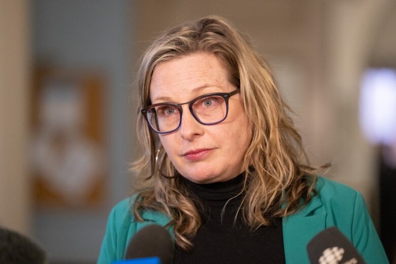 A woman with blode hair wears glasses.