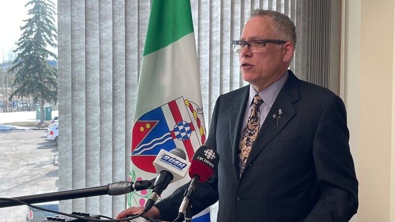 Man in suit speaks into microphones at a podium.