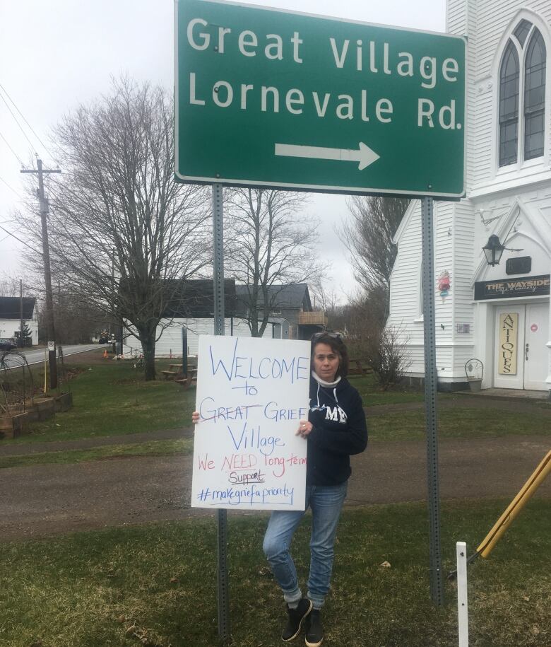 A woman holds a sign saying in part 