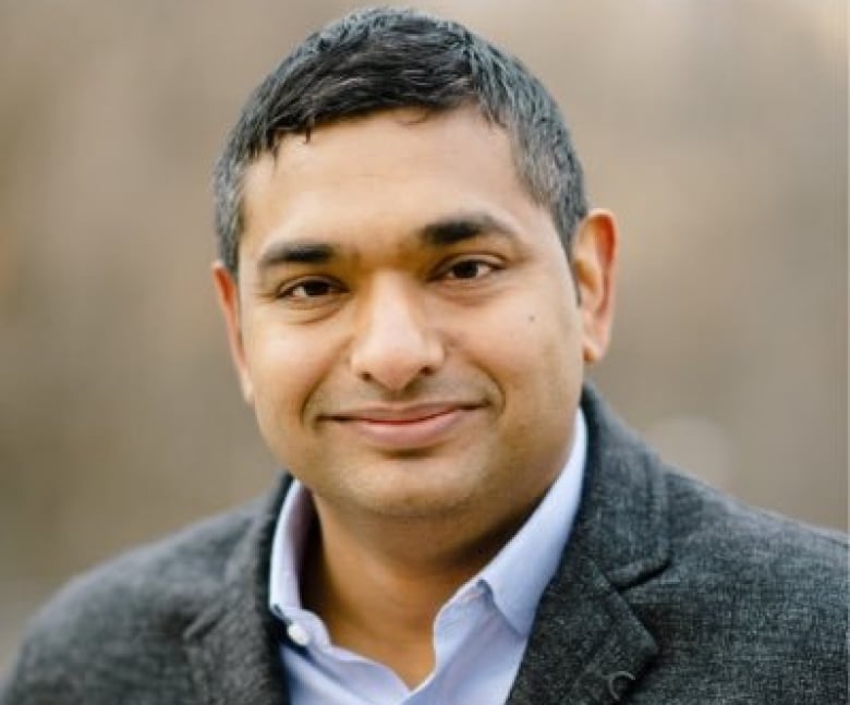 Man smiling in a grey coat.