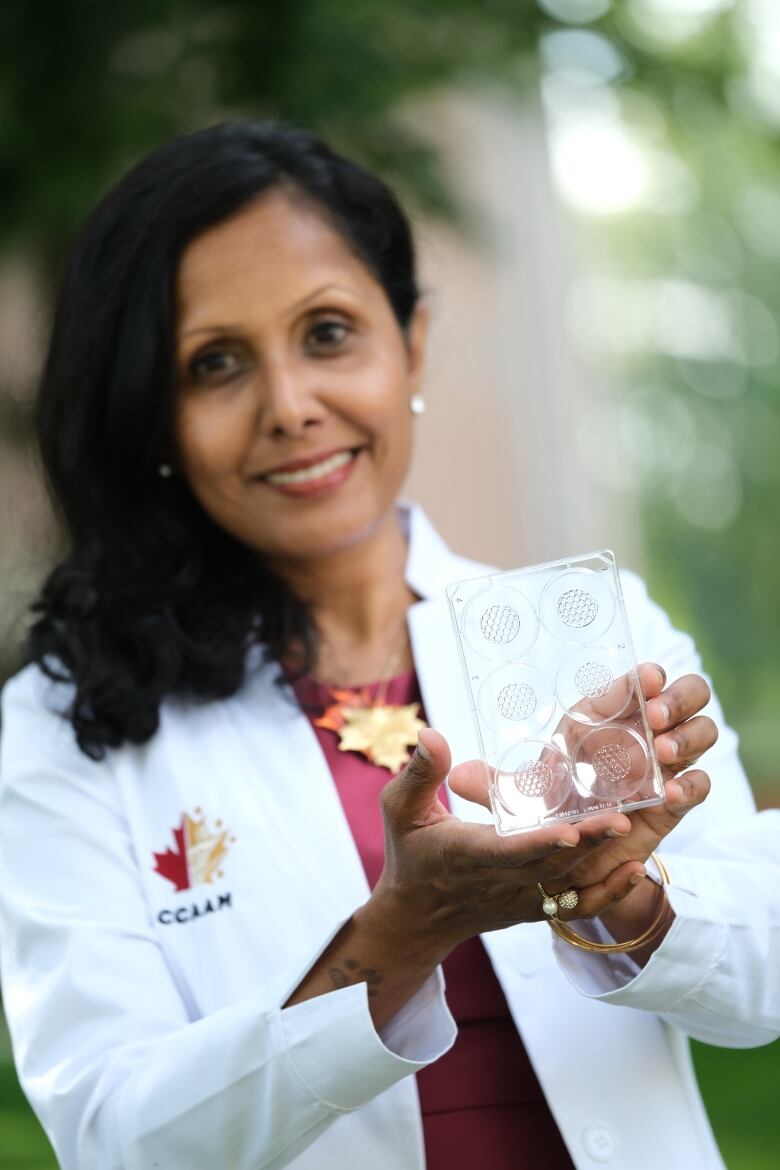 A woman holds a petrie dish