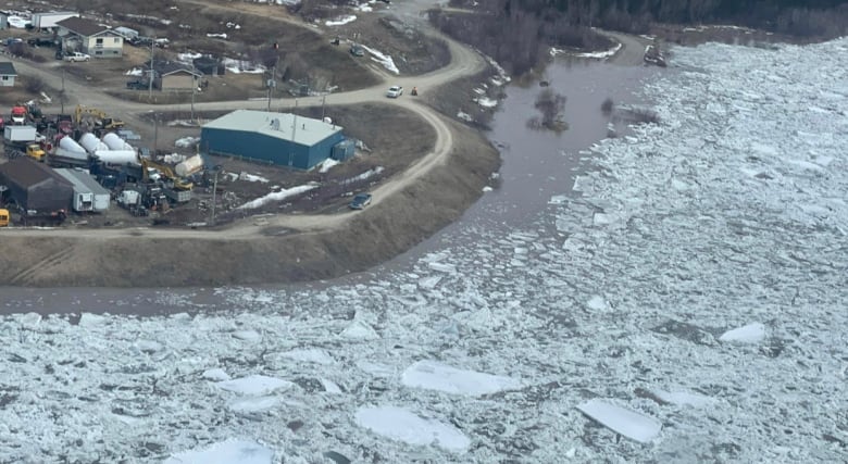 An aerial shot of a river full of pieces of ice, bending past a community 