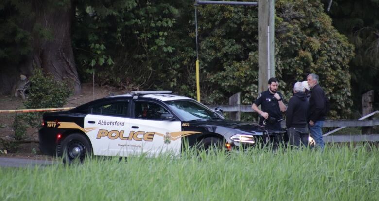 Police officers are seen at the front of a police car.