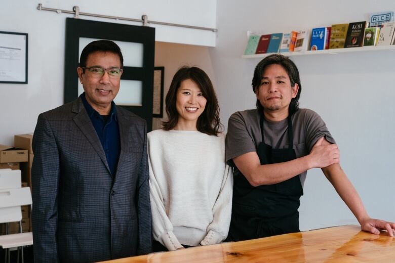 Two men and one woman pose at a counter