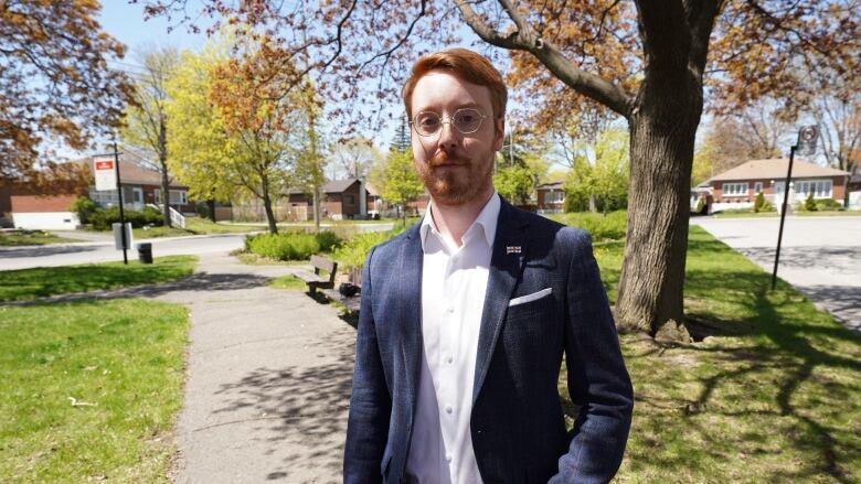 man in blue blazer posing at a park