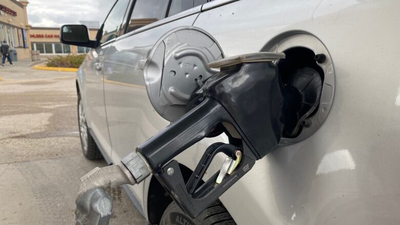 Gas pump seen beside a car. 