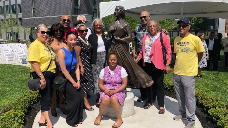 A group of people pose surrounding a statue