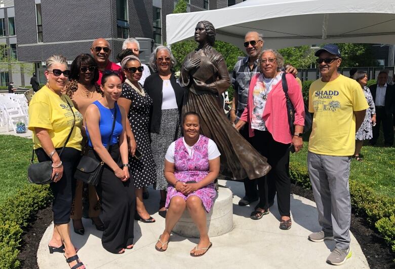 A group of people pose surrounding a statue