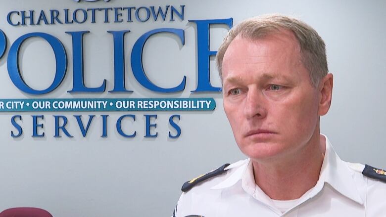 A man wearing the white shirt of a police uniform looks concerned. 