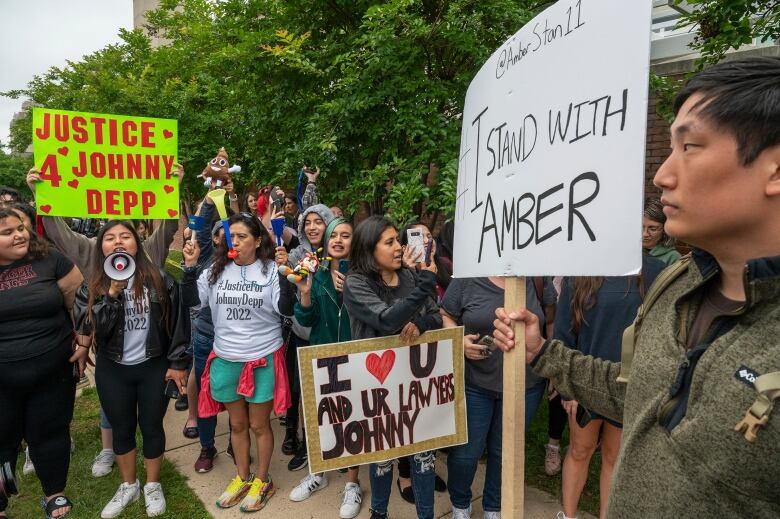 A man on the right side of the frame holds up a sign reading 