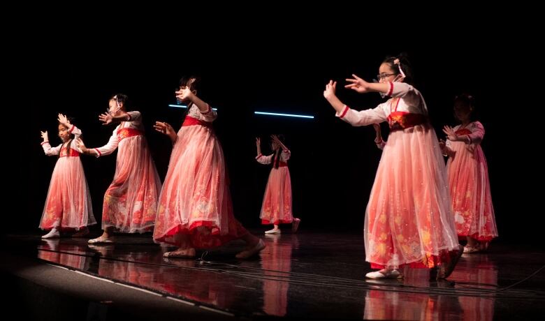 Students dancing onstage in traditional costumes 