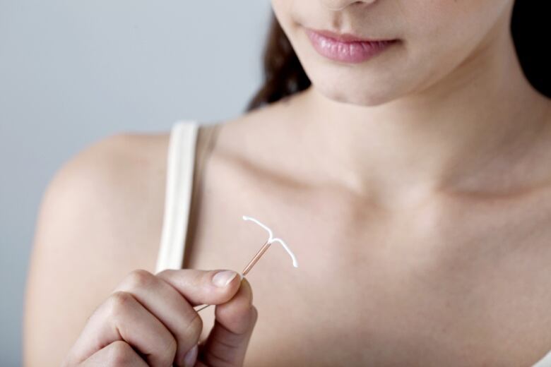 Woman holds a T-shaped IUD.