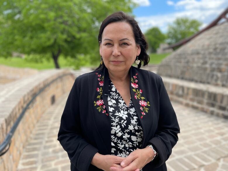 A woman stands outside, looking to camera