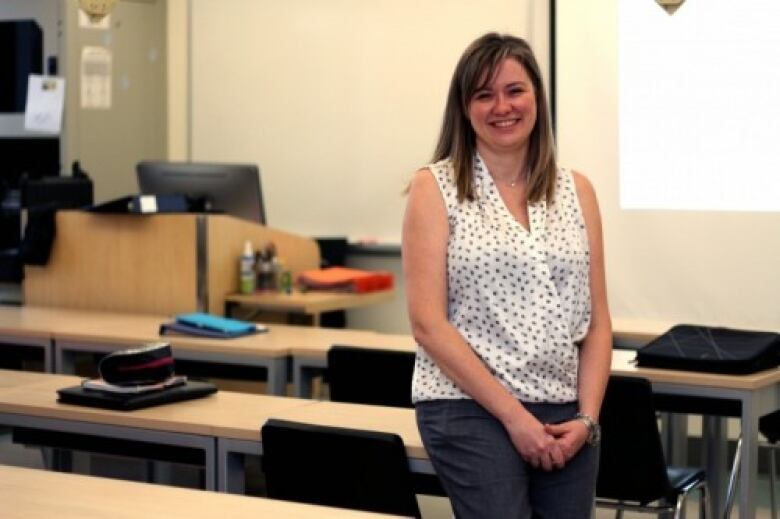 An individual smiling in a classroom.