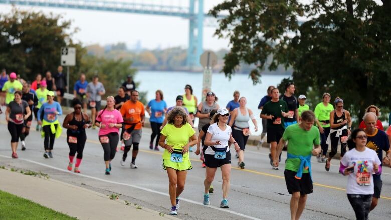 A large group of runners on a roadway with the Ambassador Bridge in the background.